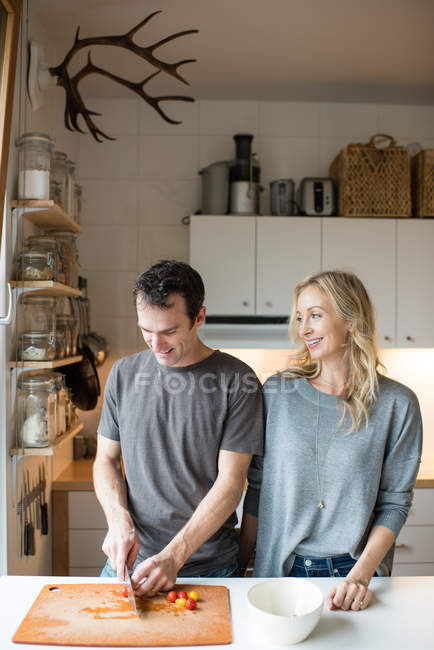 Couple chopping cherry tomatoes in kitchen — Stock Photo