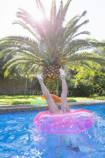 Menina mergulhando no anel inflável na piscina do jardim — Fotografia de Stock