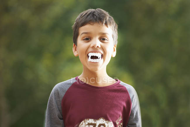 Мальчик с фальшивыми зубами вампира с клыками — стоковое фото