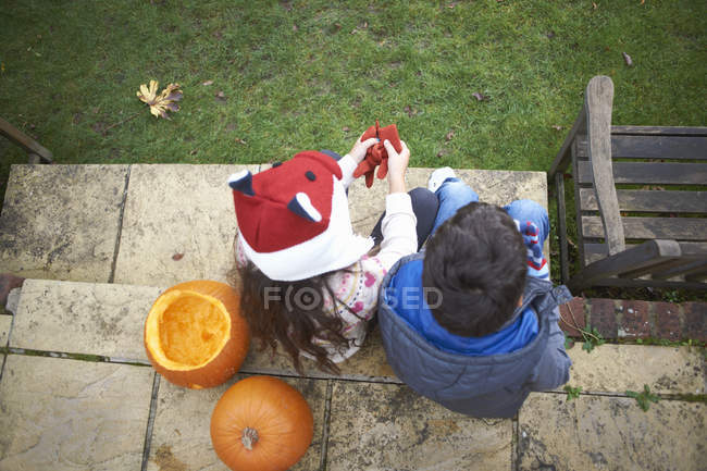 Frères et sœurs assis sur les marches dans le jardin à la maison — Photo de stock
