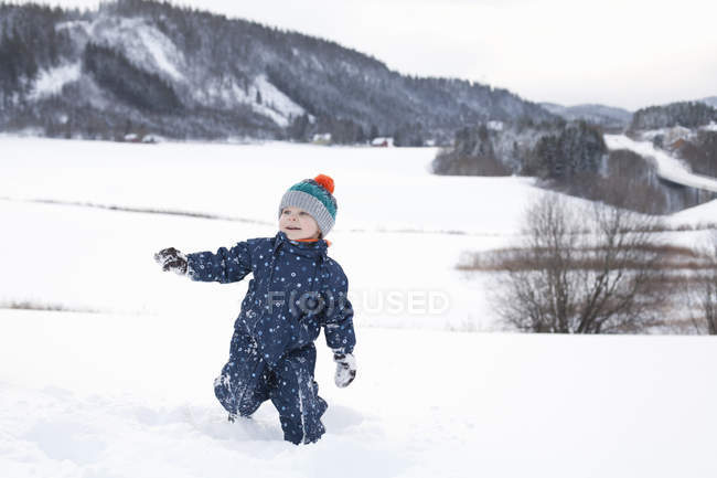 Jeune garçon jouant dans un champ de campagne enneigé — Photo de stock