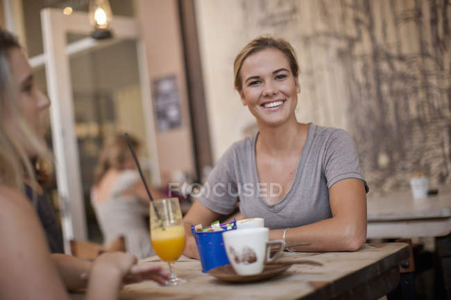 Two young adult female friends enjoying a chat in cafe — Stock Photo