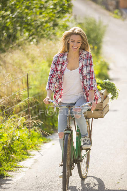 Donna sorridente in bicicletta su strada rurale — Foto stock