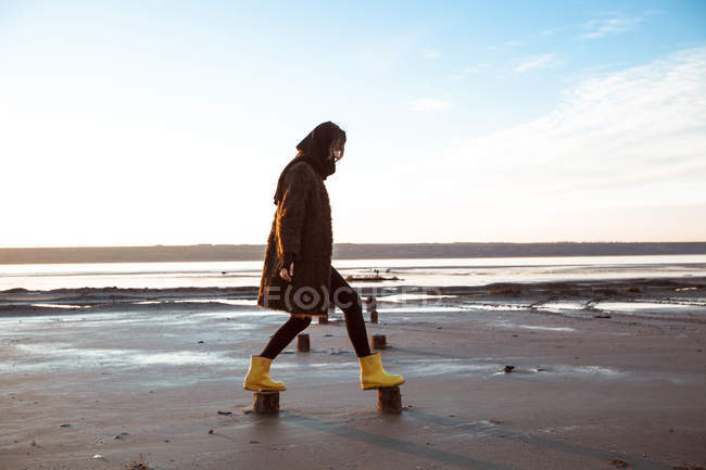 Frau balanciert auf Holzstümpfen am Strand — Stockfoto