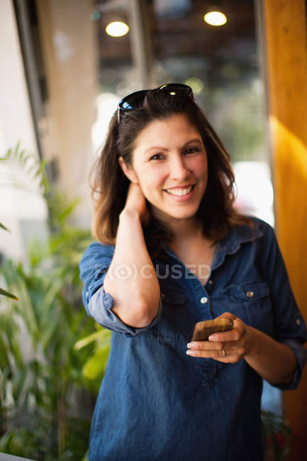 Mid adult woman using cellphone and smiling, portrait — Stock Photo