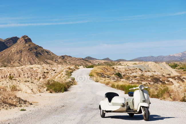 Moto e sidecar na estrada de terra com paisagem árida — Fotografia de Stock