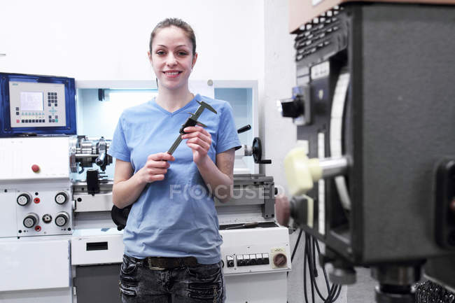 Portrait of female engineer holding tool in factory — Stock Photo