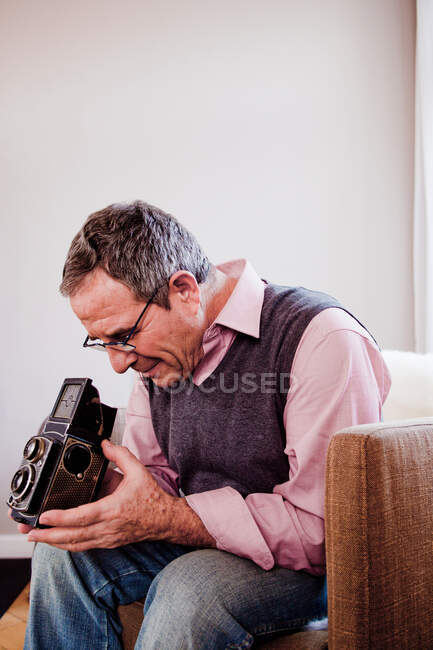 Uomo che gioca con la macchina fotografica a casa — Foto stock