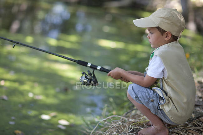 Niño pescando por arroyo - foto de stock