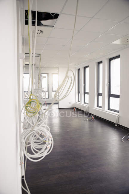 Network and power cables hanging from new office ceiling — Stock Photo