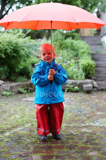 Toddler boy holding umbrella in backyard — Stock Photo
