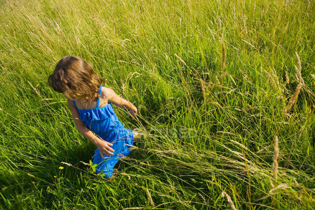 A girl walking through a field of long grass — Stock Photo