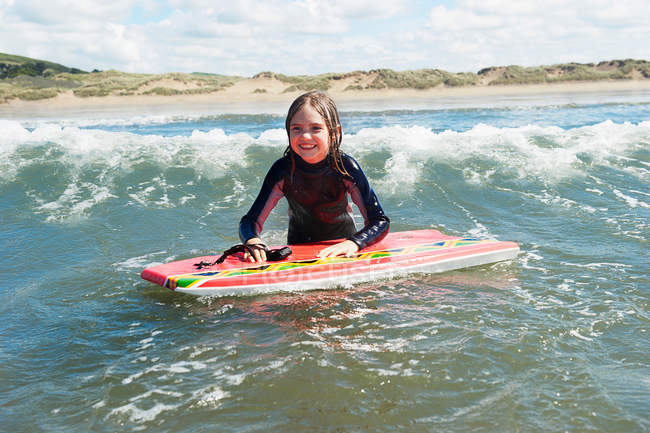 Chica joven en el mar con tabla de surf - foto de stock