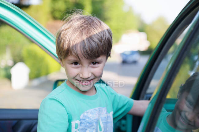 Garoto sorrindo ao lado do carro — Fotografia de Stock