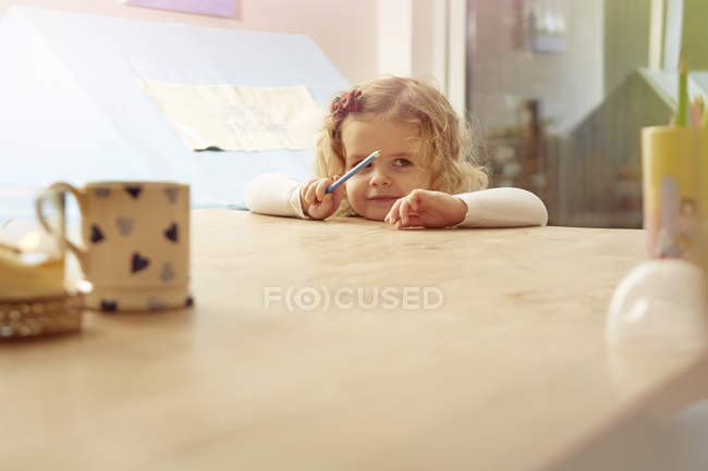 Retrato da criança feminina inclinada na mesa da cozinha — Fotografia de Stock