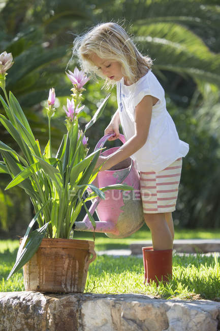 Маленька дівчинка полив сад кімнатні рослини — стокове фото