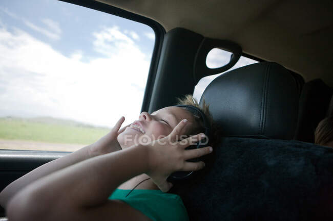 Niño escuchando música en el coche - foto de stock