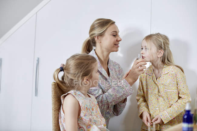 Madre e hijas jugando a disfrazarse en el dormitorio - foto de stock