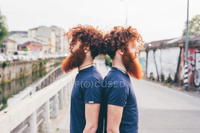 Portrait de jeunes jumeaux hipster mâles aux cheveux roux et à la barbe dos à dos sur pont — Photo de stock