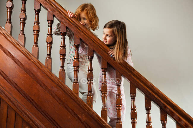 Girls looking down from staircase banister — Stock Photo
