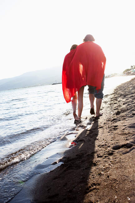 Couple walking down beach — Stock Photo