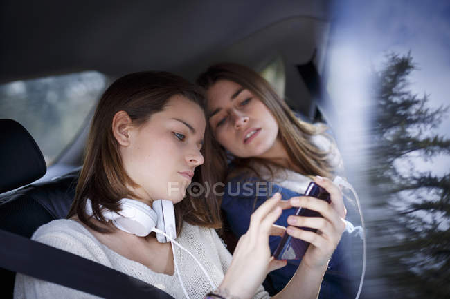 Sœurs écoutant ensemble de la musique dans des écouteurs en voiture — Photo de stock