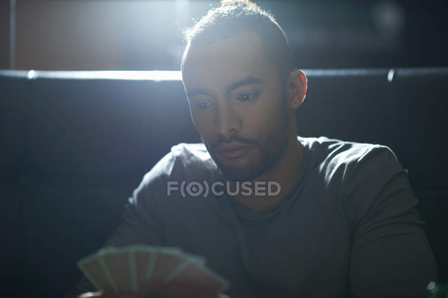 Young man with hand of playing cards playing cards in traditional UK pub — Stock Photo