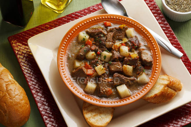 Assiette de ragoût avec tranches de pain servi sur la table — Photo de stock