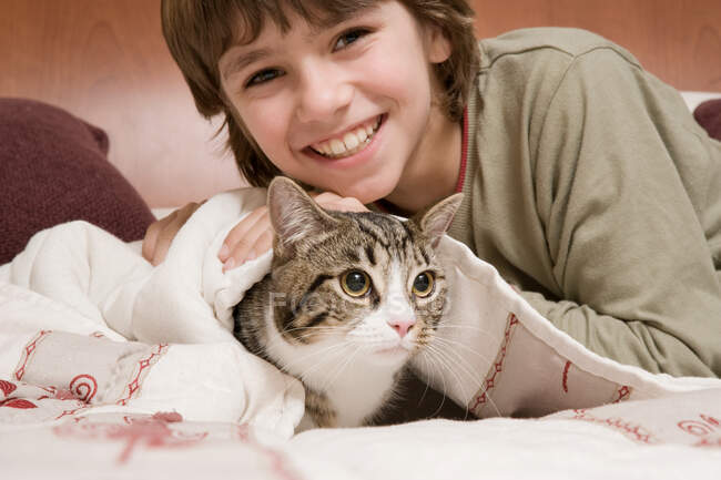 Retrato de niño con gato en la cama - foto de stock