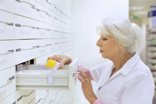 Female pharmacist searching for medicine for prescription — Stock Photo