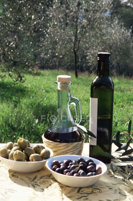 Оливкової олії і оливки на столі в саду — стокове фото
