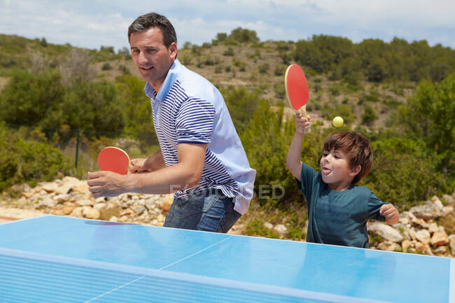 Отец и сын играют в настольный теннис — стоковое фото