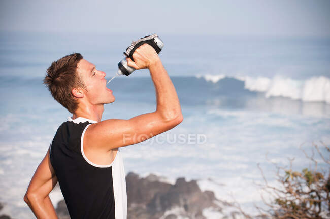 Runner drinking water on beach — Stock Photo
