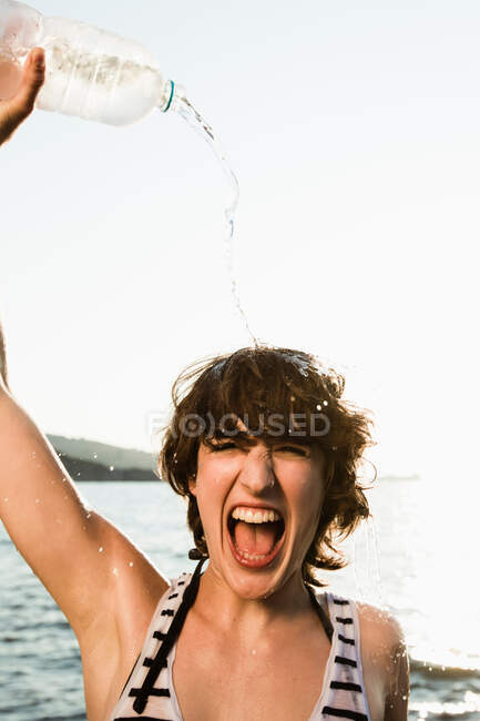Mulher derramando água sobre si mesma na praia — Fotografia de Stock