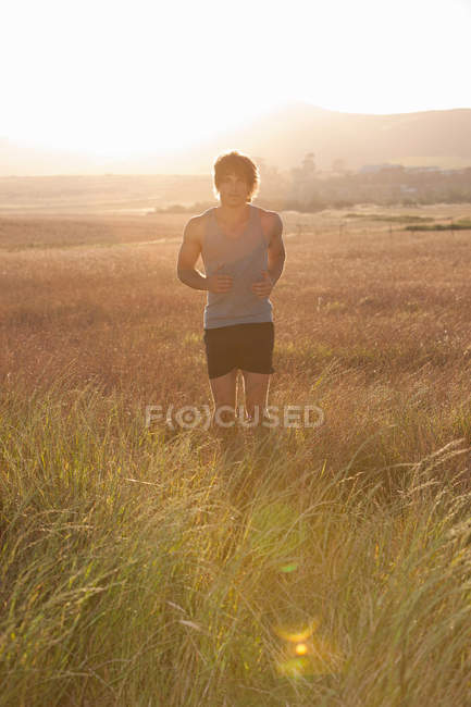 Homem correndo em grama alta — Fotografia de Stock