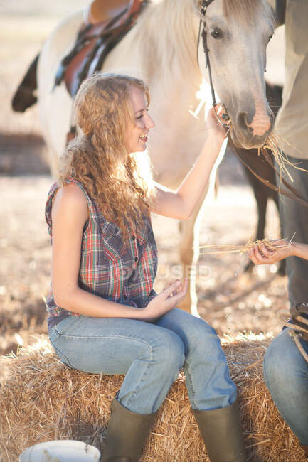 Jeune femme tenant la bride du cheval — Photo de stock
