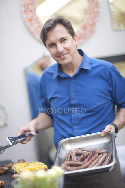 Uomo maturo barbecue salsicce — Foto stock