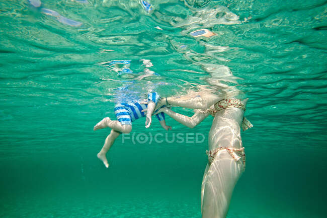 Madre enseñando a nadar a un niño pequeño - foto de stock