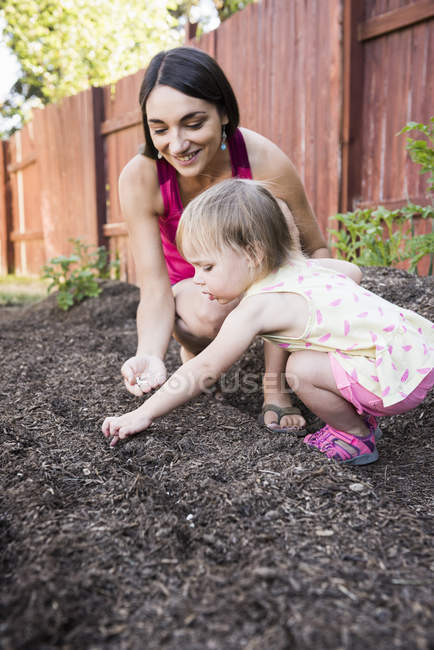 Mother and young daughter planting seeds in garden — Stock Photo