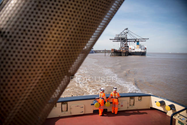 Trabalhadores de rebocadores no convés do rebocador no mar com guindastes no fundo — Fotografia de Stock