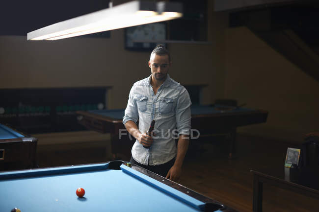 Man with beer standing at pool table — Stock Photo