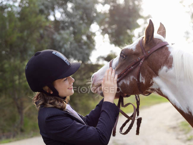 Девочка-подросток гладит лошадь — стоковое фото