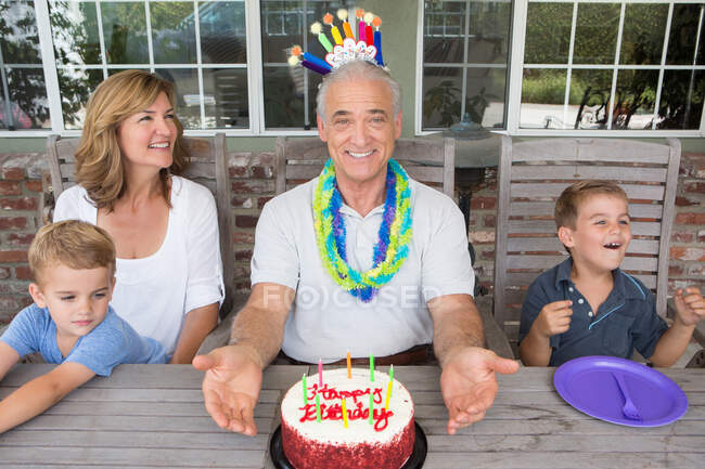 Uomo anziano con torta di compleanno e famiglia, ritratto — Foto stock