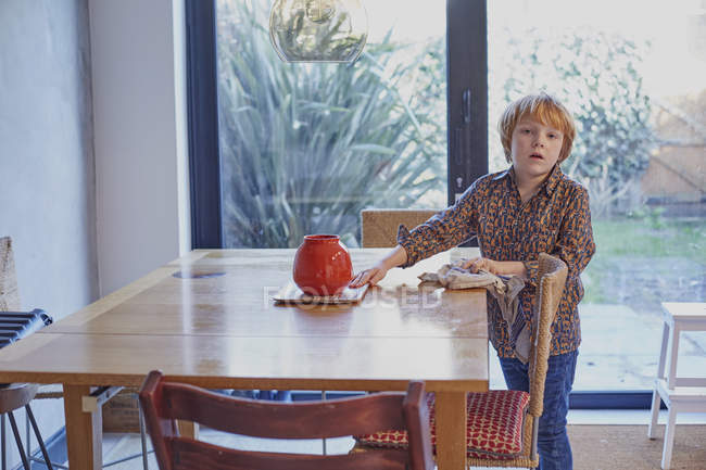Мальчик вытирает и убирает обеденный стол — стоковое фото