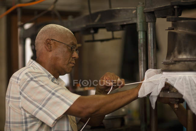Hat maker tying fabric onto mould in workshop — Stock Photo