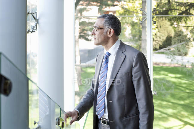 Зрілий бізнесмен дивиться з офісної будівлі — стокове фото