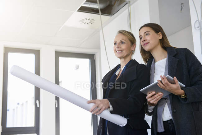 Businesswomen with blueprint inspecting in new office — Stock Photo