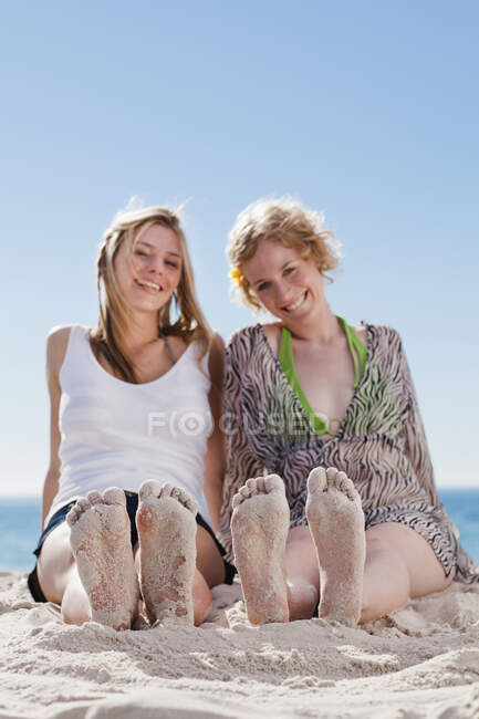 Женщины с песчаными ногами на пляже — стоковое фото