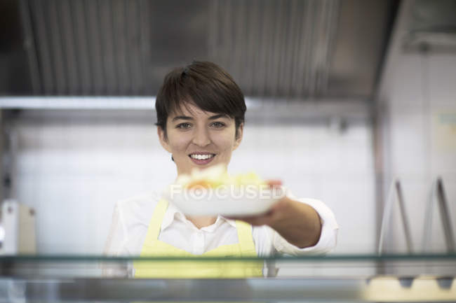Молода жінка передає їжу клієнту, в магазині фаст-фуду — стокове фото