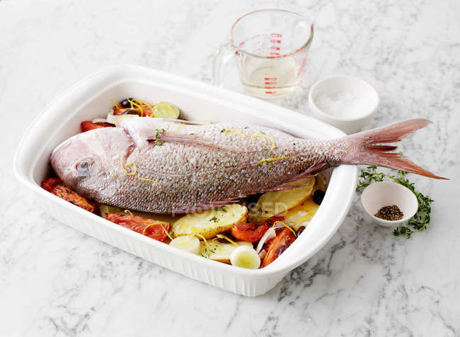 Dish of baked fish with vegetables served on table — Stock Photo